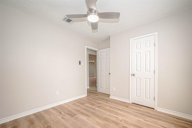 unfurnished bedroom with light wood-type flooring, visible vents, a textured ceiling, and baseboards