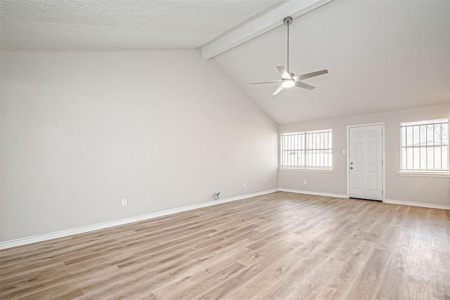 empty room featuring light wood-style floors, baseboards, a wealth of natural light, and beamed ceiling