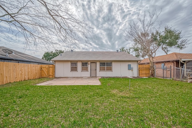 back of property with a lawn, a patio area, a fenced backyard, and a gate