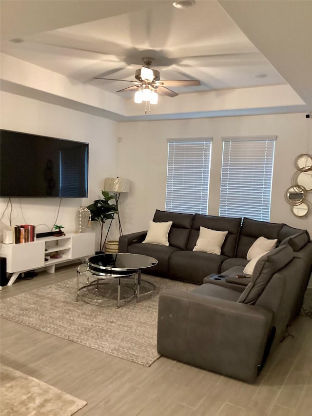 living room featuring a tray ceiling, hardwood / wood-style flooring, and ceiling fan