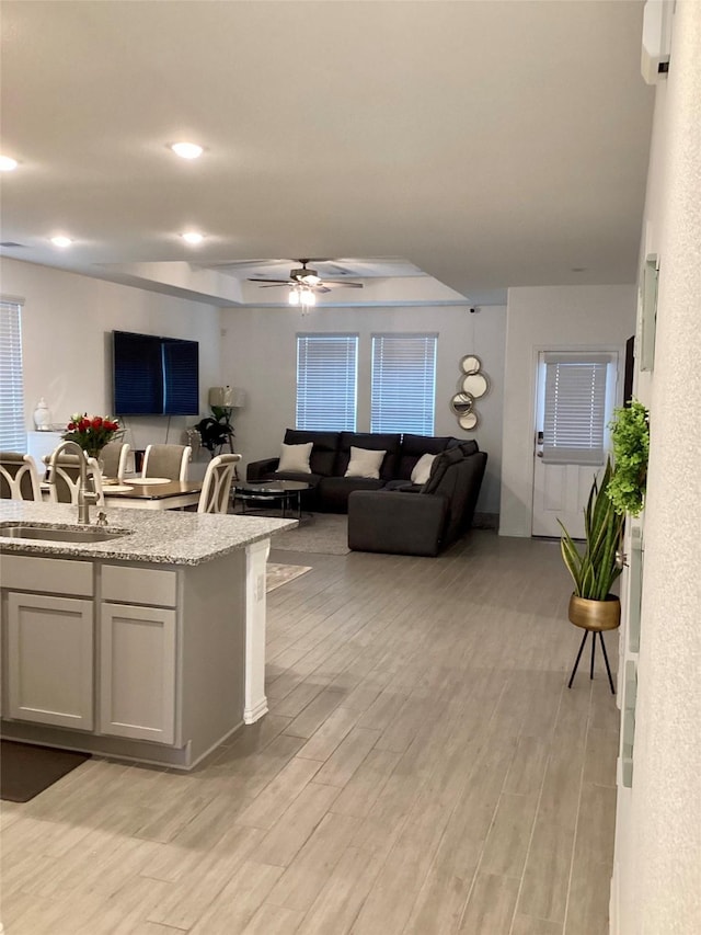 kitchen featuring light hardwood / wood-style flooring, sink, ceiling fan, white cabinets, and light stone countertops