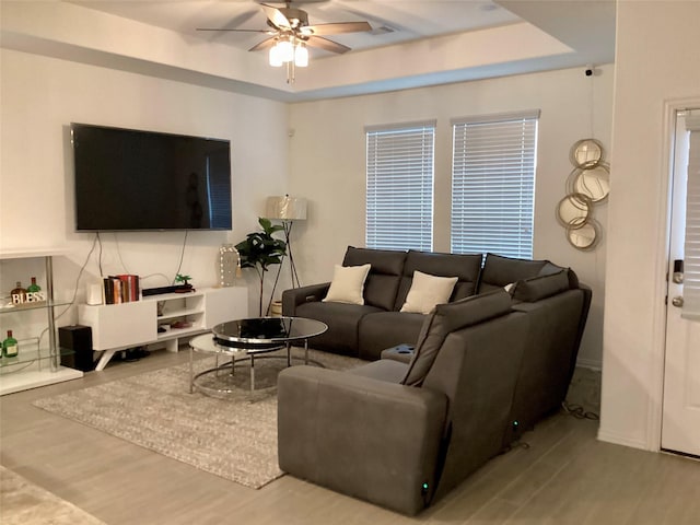 living room featuring a tray ceiling, hardwood / wood-style flooring, and ceiling fan