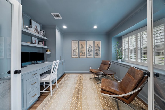 office with light wood-type flooring, crown molding, and built in desk