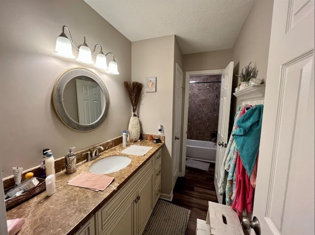 bathroom with shower / bathing tub combination, vanity, wood-type flooring, and a textured ceiling