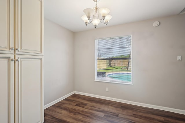 unfurnished dining area with a notable chandelier, baseboards, and dark wood-style floors