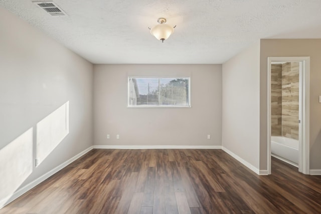 empty room featuring visible vents, baseboards, a textured ceiling, and wood finished floors