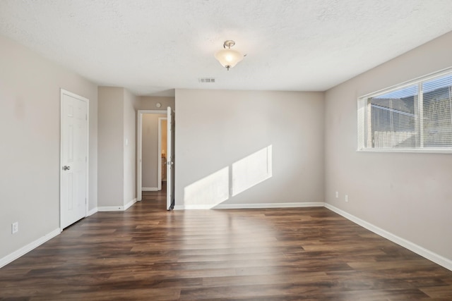 unfurnished room featuring visible vents, baseboards, wood finished floors, and a textured ceiling