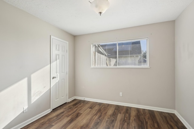 empty room featuring dark wood-type flooring and baseboards