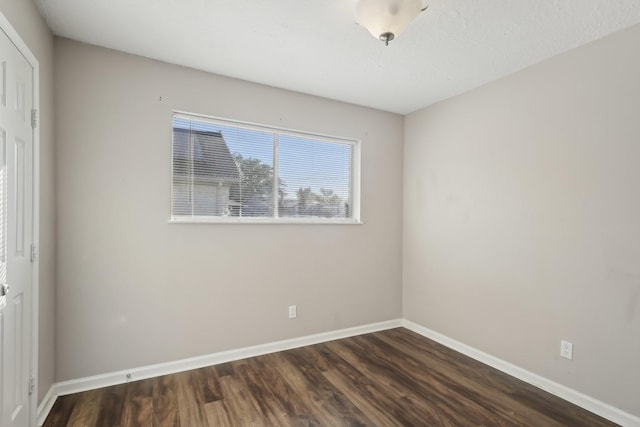 unfurnished room featuring baseboards and dark wood finished floors