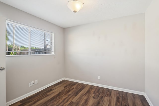 spare room featuring baseboards and dark wood-style floors