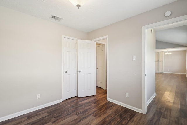 unfurnished bedroom with visible vents, baseboards, an inviting chandelier, and dark wood finished floors