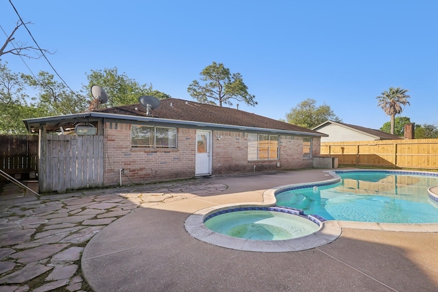 view of pool with a pool with connected hot tub, fence, and a patio