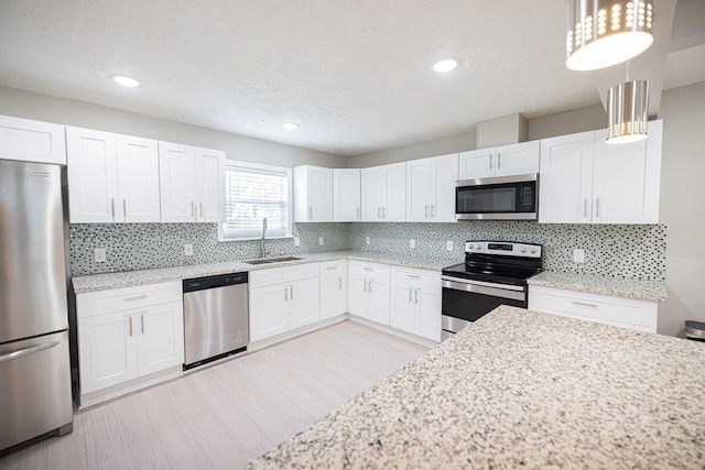 kitchen featuring hanging light fixtures, white cabinetry, appliances with stainless steel finishes, and sink