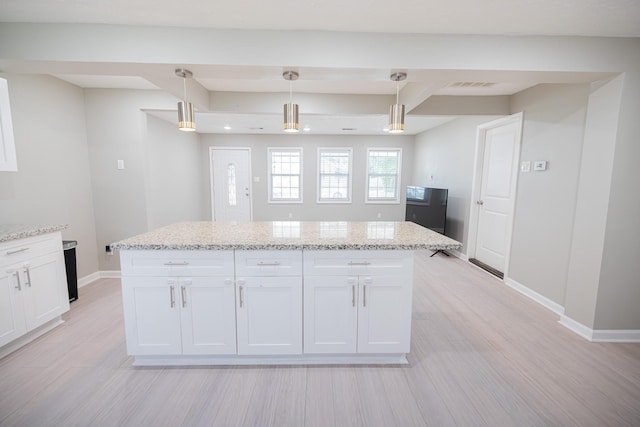 kitchen featuring beam ceiling, light stone counters, decorative light fixtures, a center island, and white cabinetry