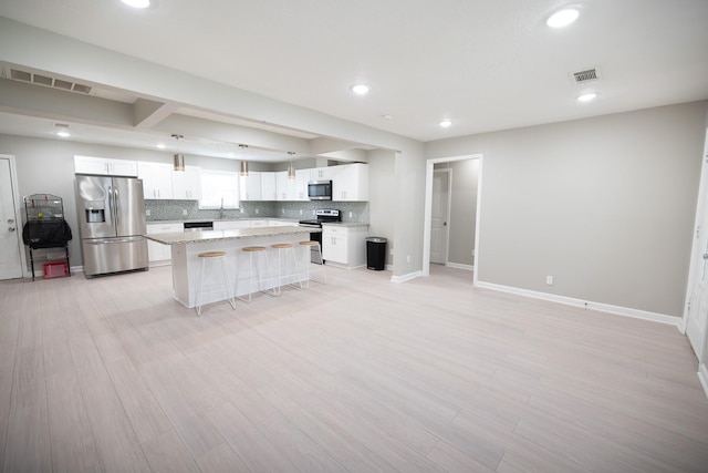 kitchen with tasteful backsplash, hanging light fixtures, stainless steel appliances, a kitchen island, and white cabinetry