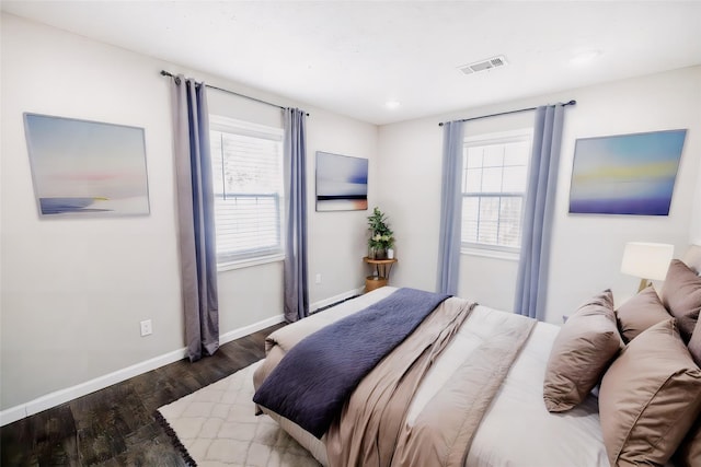 bedroom with multiple windows and dark hardwood / wood-style flooring