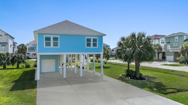 coastal home with an attached garage, stairs, roof with shingles, a carport, and a front lawn