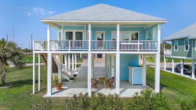 rear view of house featuring a patio area, roof with shingles, a yard, and stairway