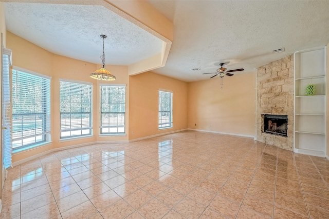 unfurnished living room featuring a healthy amount of sunlight, built in shelves, a stone fireplace, and a textured ceiling