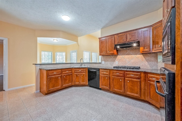 kitchen featuring kitchen peninsula, black appliances, sink, tasteful backsplash, and stone countertops