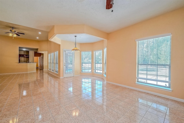 tiled empty room featuring ceiling fan and a textured ceiling