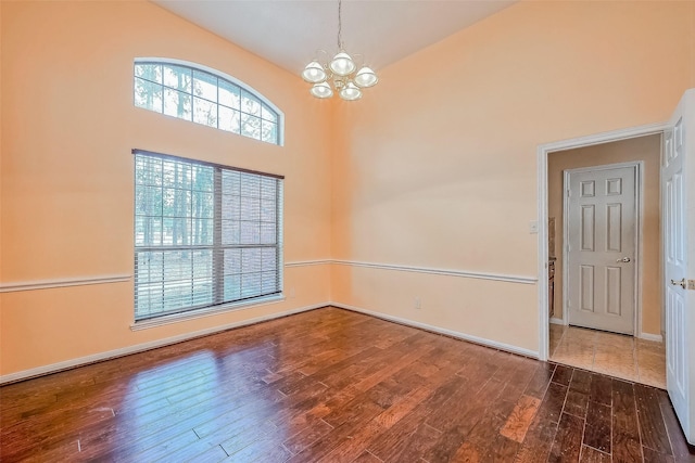 spare room featuring high vaulted ceiling, a chandelier, and dark hardwood / wood-style floors