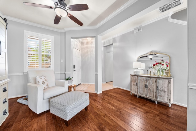 sitting room featuring ornamental molding, dark wood-type flooring, ceiling fan, and a barn door