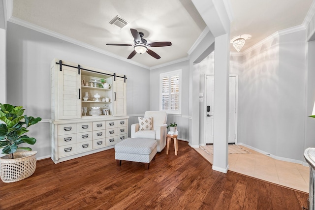 sitting room with ornamental molding, hardwood / wood-style floors, ceiling fan, and a barn door