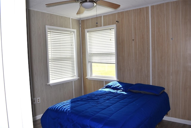 bedroom featuring crown molding, wood walls, and ceiling fan