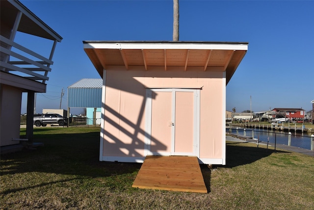 view of outdoor structure featuring a water view and a lawn