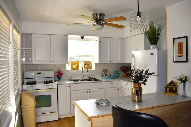 kitchen with white appliances, white cabinetry, sink, and decorative light fixtures