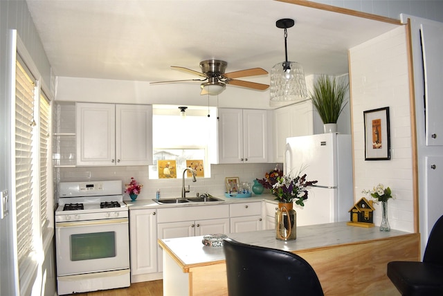 kitchen featuring sink, white appliances, hanging light fixtures, and white cabinetry