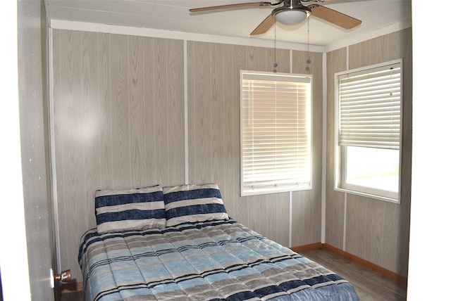 bedroom with hardwood / wood-style flooring, ceiling fan, and wood walls