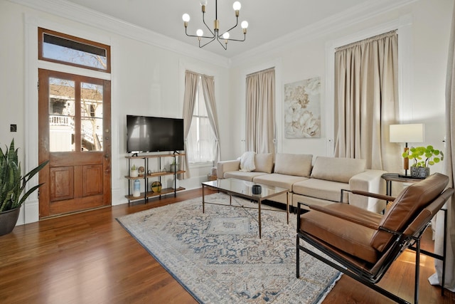 living area featuring a healthy amount of sunlight, an inviting chandelier, ornamental molding, and wood finished floors