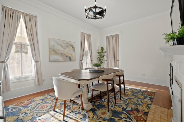 dining area with baseboards, a notable chandelier, ornamental molding, and wood finished floors