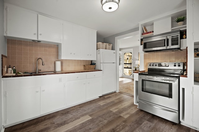 kitchen with tile counters, dark wood-type flooring, stainless steel appliances, white cabinetry, and a sink