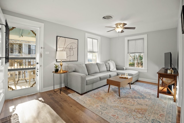 living area featuring a ceiling fan, baseboards, visible vents, and wood finished floors