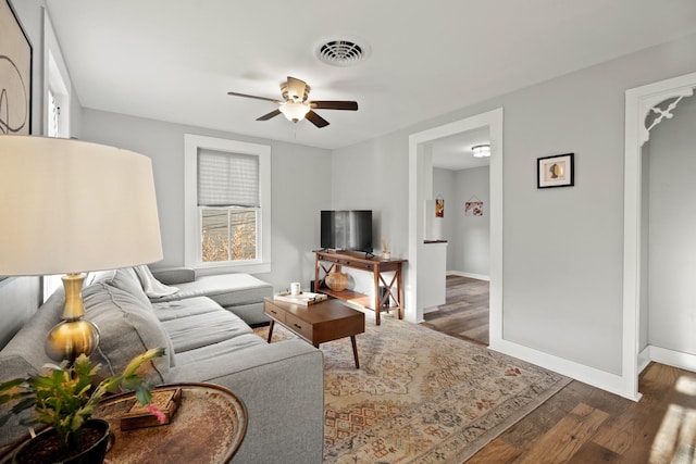 living room featuring a ceiling fan, baseboards, visible vents, and wood finished floors