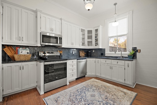 kitchen with wood finished floors, appliances with stainless steel finishes, a sink, and white cabinets