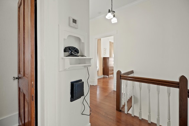 corridor with ornamental molding, baseboards, an upstairs landing, and wood finished floors