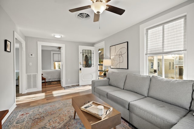 living room with baseboards, visible vents, and wood finished floors