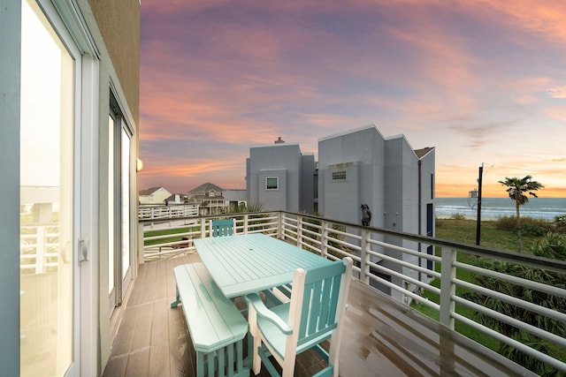 balcony with outdoor dining area and a water view