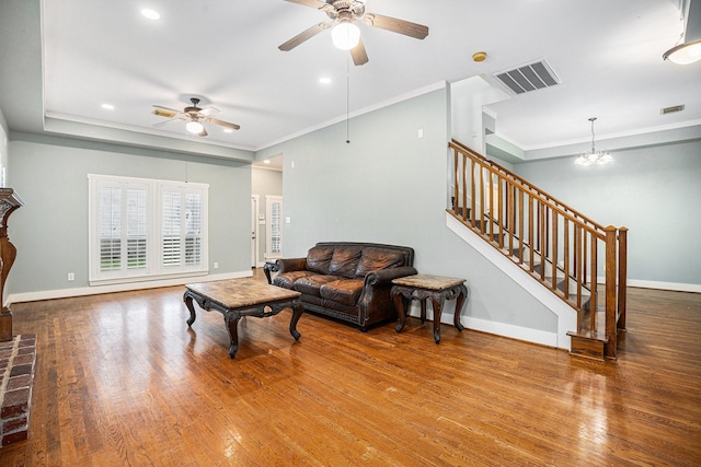 living room featuring hardwood / wood-style flooring, crown molding, and ceiling fan with notable chandelier