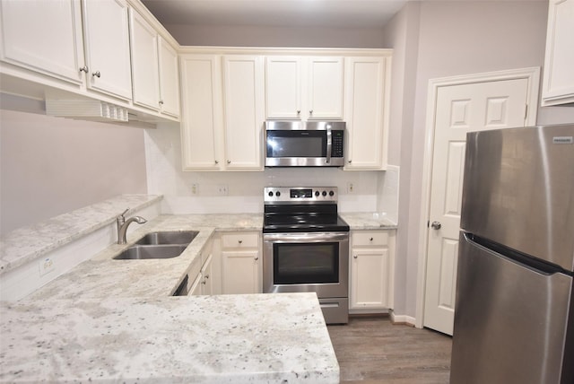 kitchen featuring appliances with stainless steel finishes, sink, backsplash, light stone counters, and hardwood / wood-style flooring