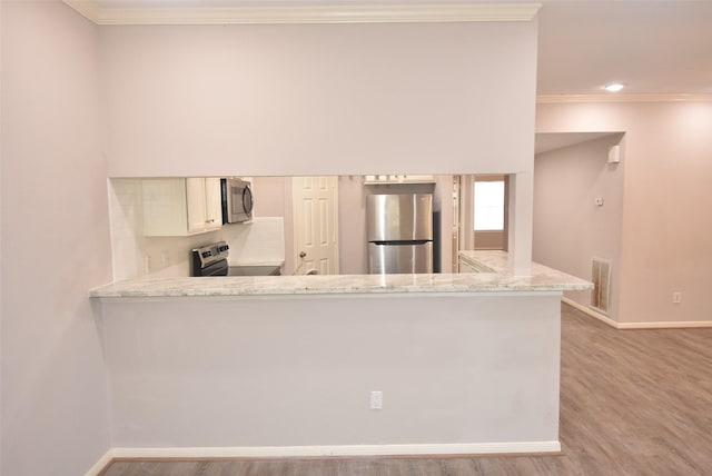 12565 Melville Dr Unit 224, Montgomery, TX 77356 - kitchen with appliances with stainless steel finishes, light stone counters, light wood-type flooring, kitchen peninsula, and ornamental molding