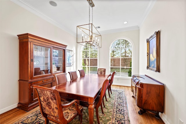 dining space featuring light wood-style flooring, baseboards, ornamental molding, and a chandelier