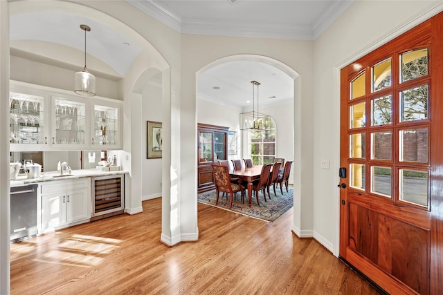 bar featuring beverage cooler, light wood-style flooring, dishwasher, and a sink