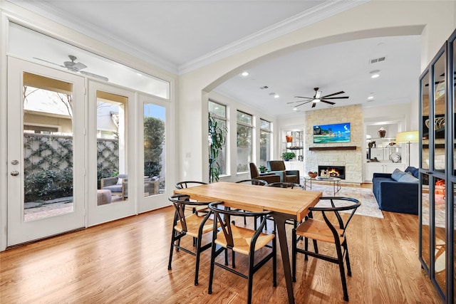 dining space featuring visible vents, plenty of natural light, a stone fireplace, and ornamental molding