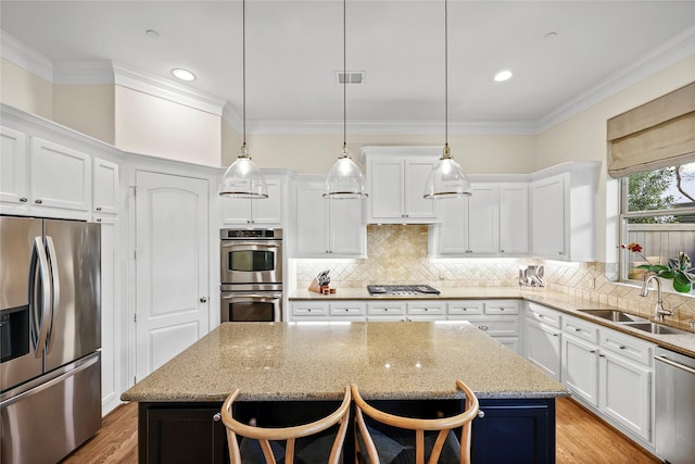 kitchen with visible vents, a sink, a center island, appliances with stainless steel finishes, and crown molding