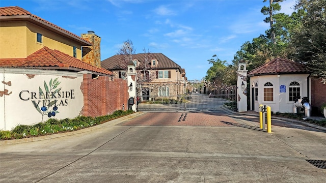 view of street with a gated entry, curbs, and a gate